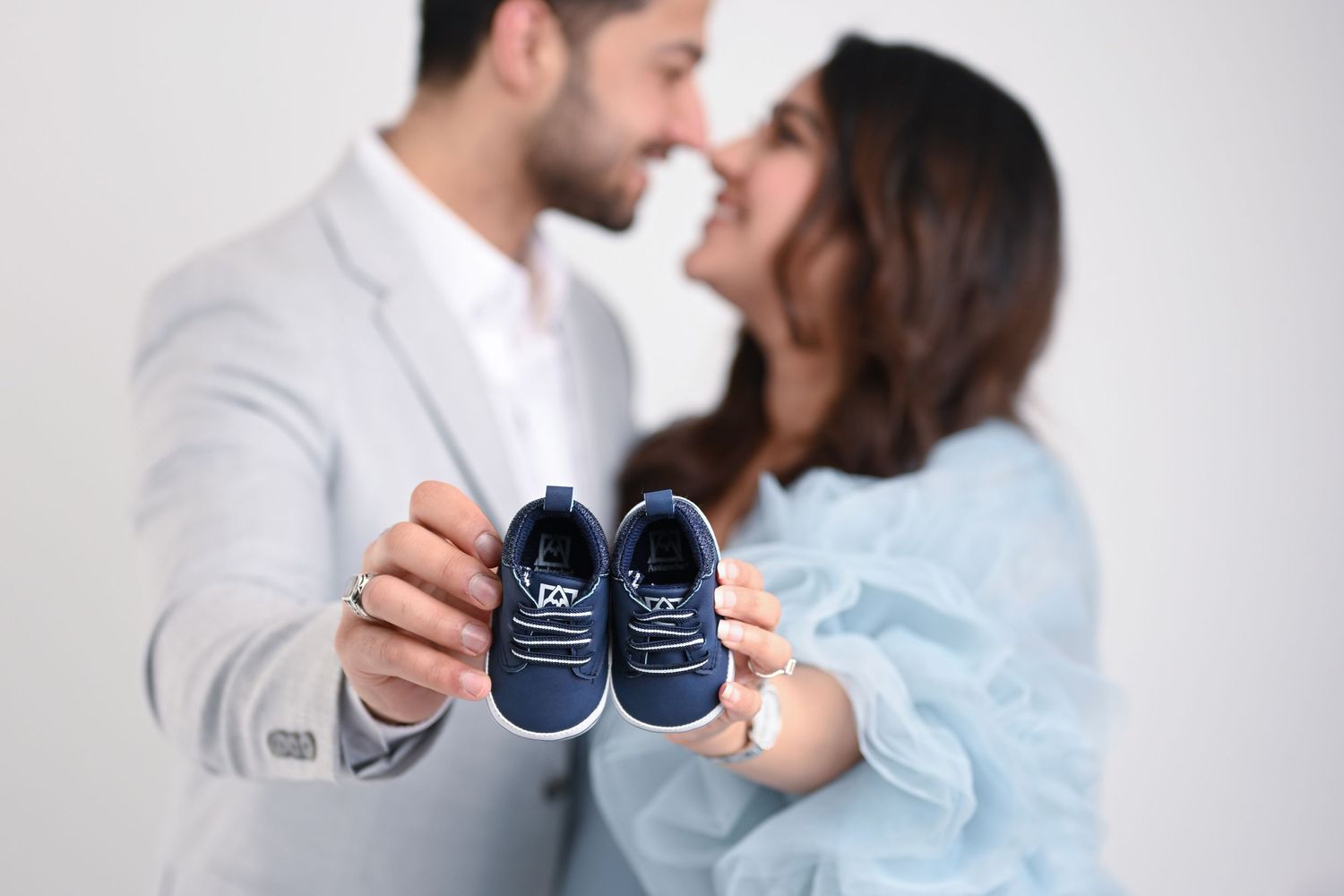 Expectant couple sharing intimate moment with tiny blue baby shoes.