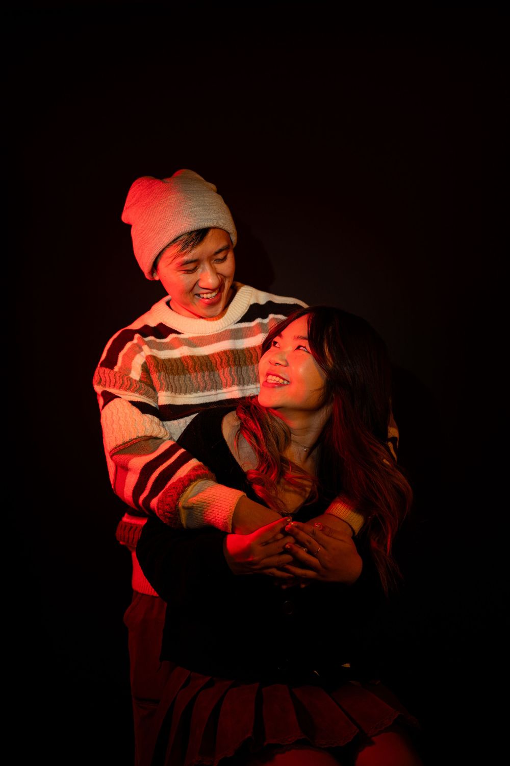 Dramatic red-lit portrait series showing intimate emotional moments in dark setting.