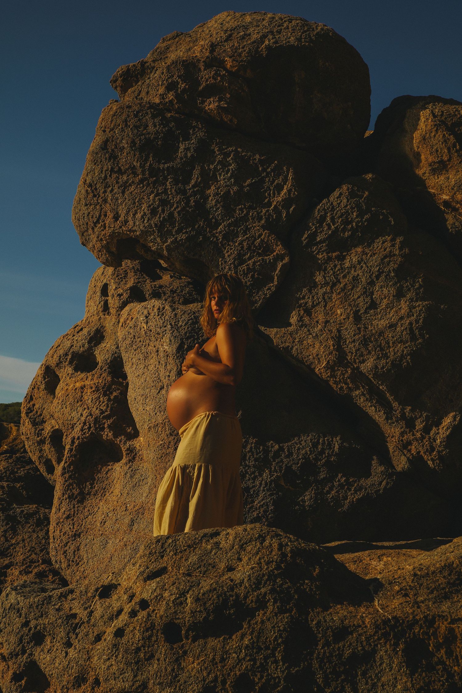 Silhouettes against large rock formations during golden hour create a dramatic natural scene.