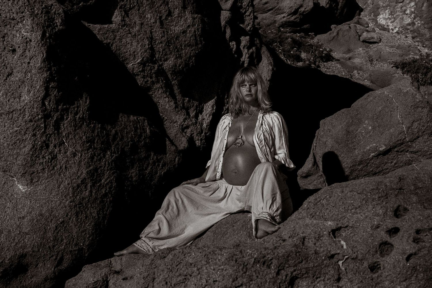 Atmospheric black and white photos of figure in flowing dress among rock formations.