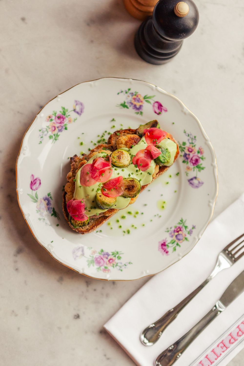 Elegant plated appetizer with pink garnish and microgreens served on a vintage floral china plate.