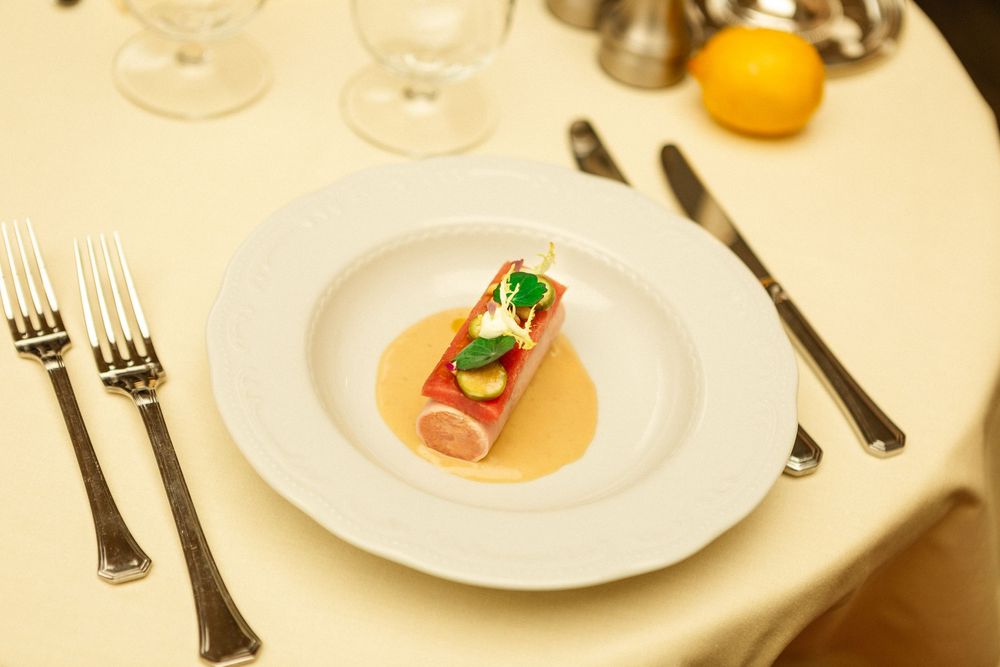 Place settings on an elegant dining table with white plates and glassware in a warm-toned ambiance.