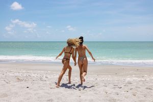 Sandy beach shoreline with turquoise waters and couple walking along the water's edge.