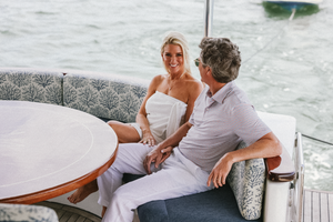 Couple relaxing on cushioned yacht seating area with ocean views.
