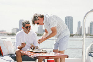 Two people enjoying refreshments at a wooden table on a luxury yacht deck.