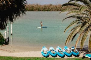 Calm lagoon with palm trees and blue inflatable water equipment visible along the shoreline.