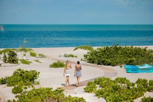 Panoramic view of tropical beach with turquoise waters and lush coastal vegetation.