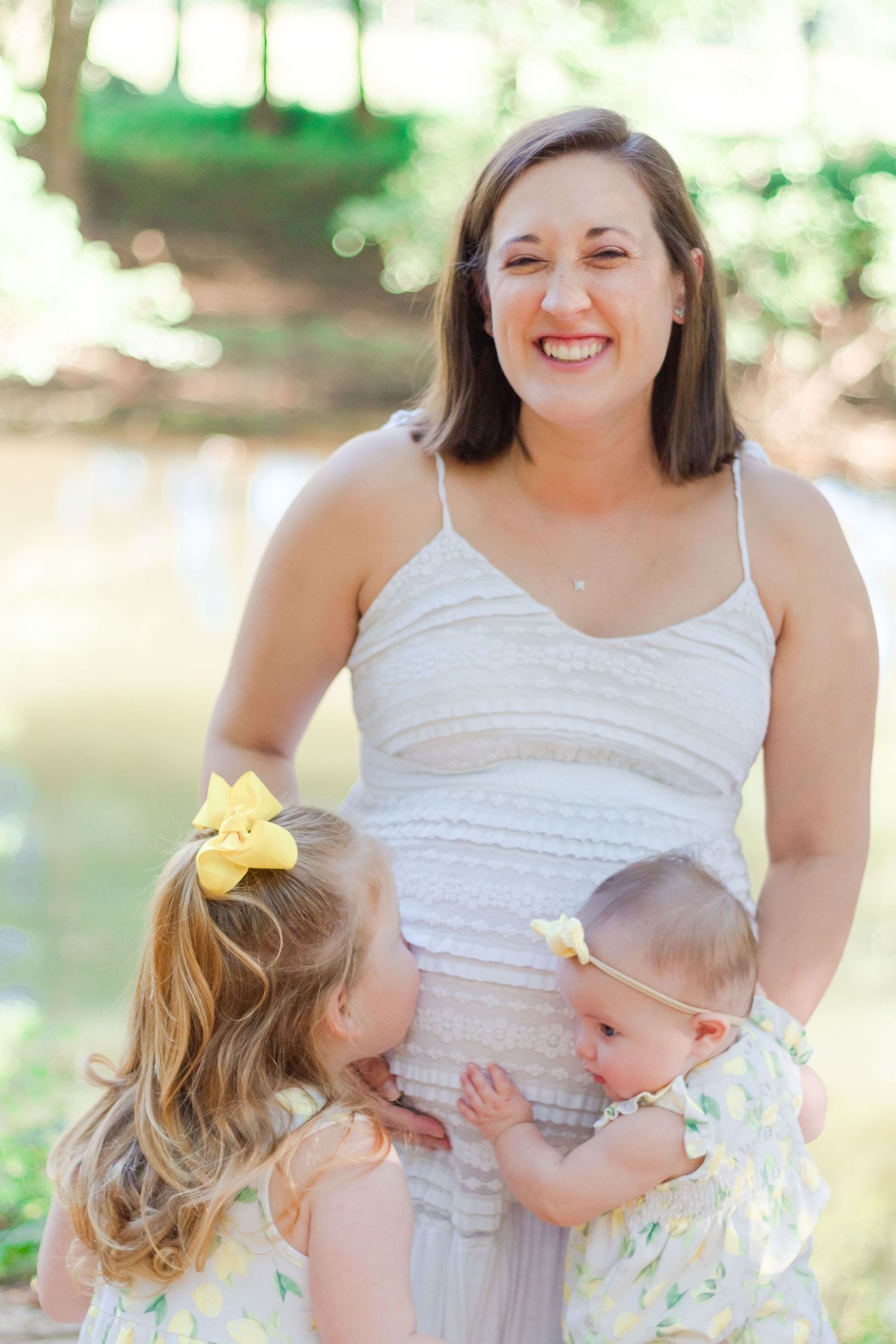 pregnant mother with two small children embracing belly