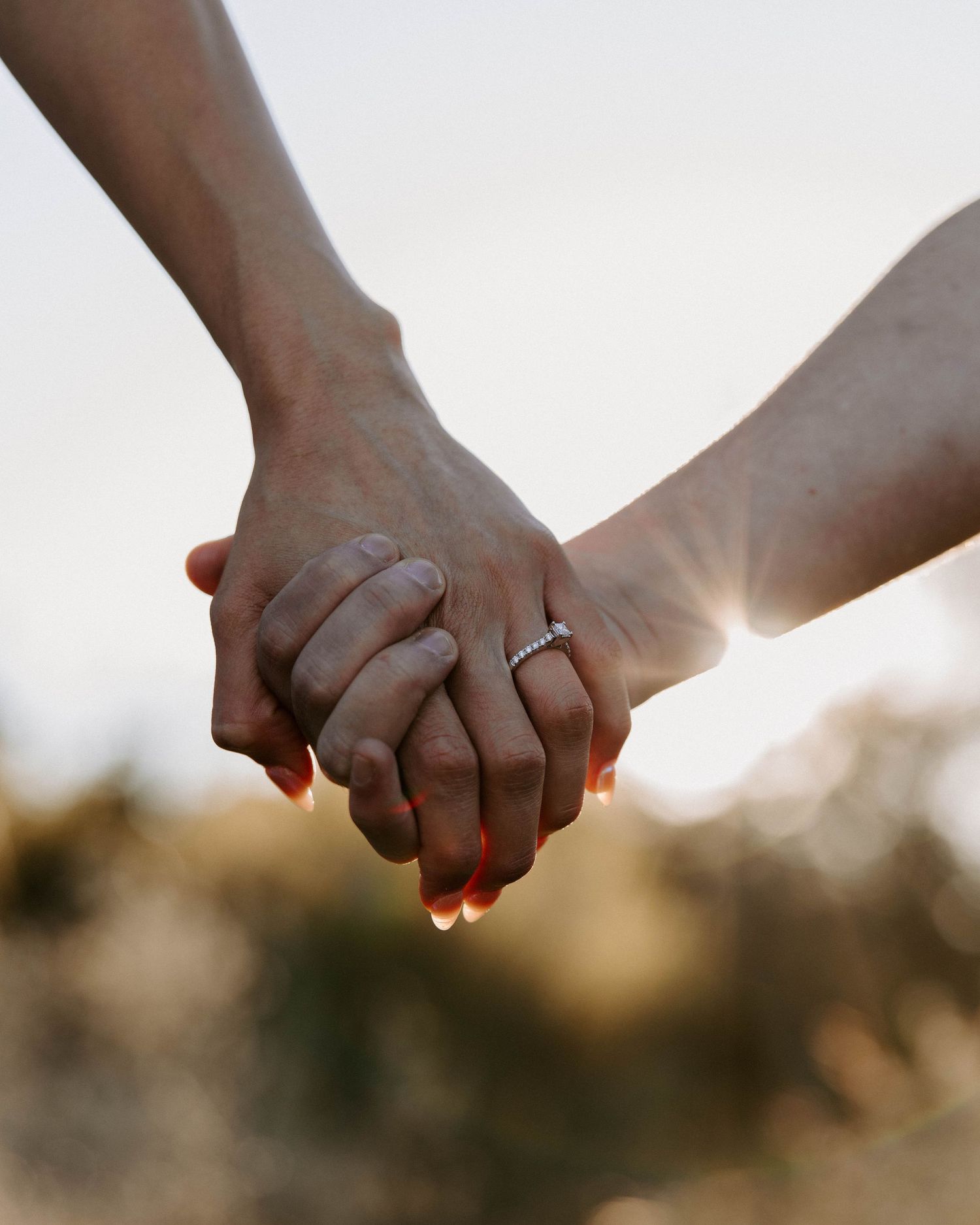 San Antonio Engagement Photography. Two hands clasped together with a wedding ring glowing in golden sunset light.
