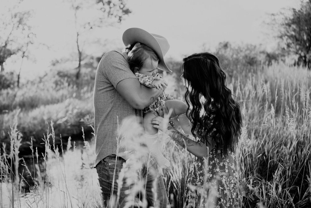 Black and white portrait of a couple embracing in a field of tall grass.