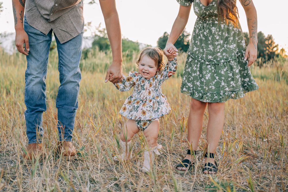 Low angle shot of family walking through golden grass field holding hands.