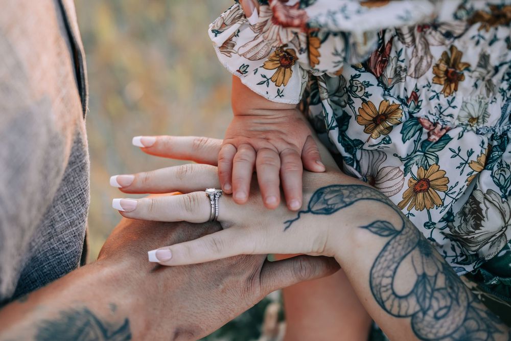 Close-up of hands showing wedding rings with floral dress details.