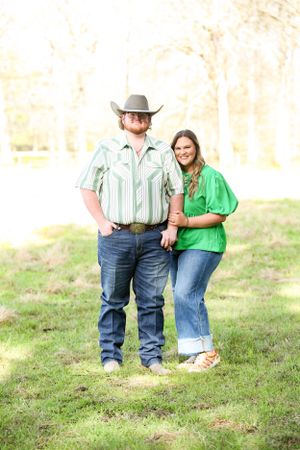 Casual couple portraits taken on grassy hillside with rustic country styling.