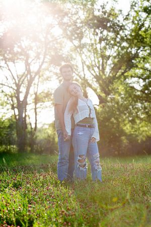 Couple standing in a sunlit wildflower field during golden hour.