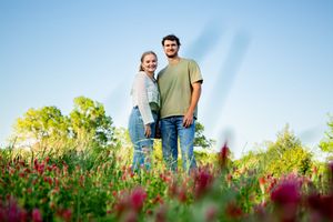 Couple photographed from a distance in blooming wildflower meadow.