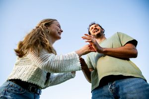 Playful couple interacting against blue sky background during photo session.
