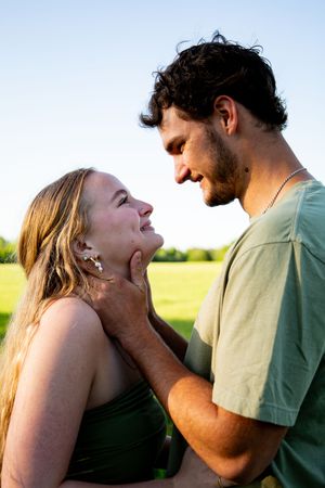 Intimate moment captured between couple during sunset photoshoot in field.