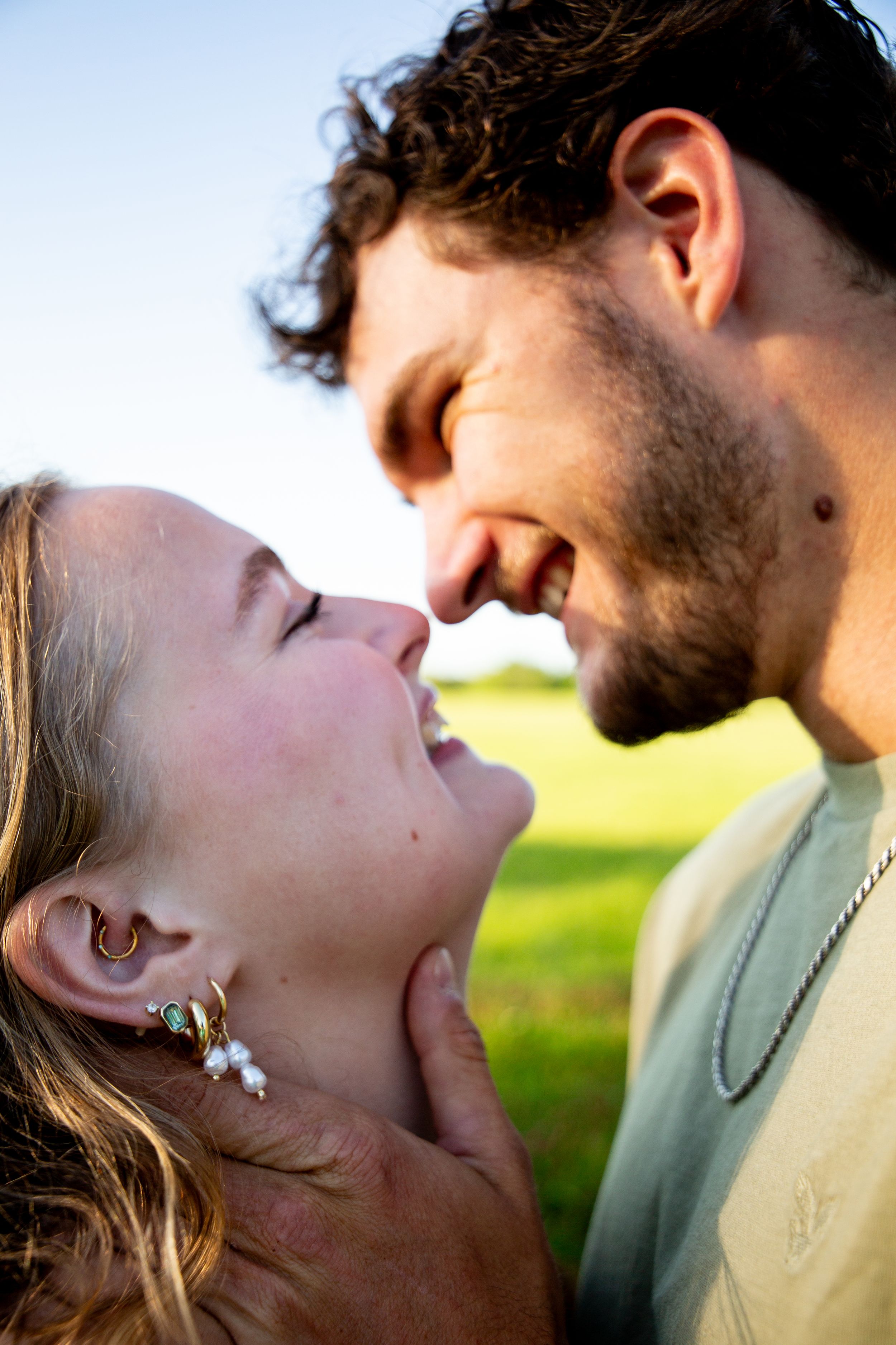Romantic couple sharing intimate moments at sunset in a field with warm golden lighting.