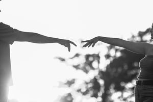 Silhouetted figures embracing against a bright white background.