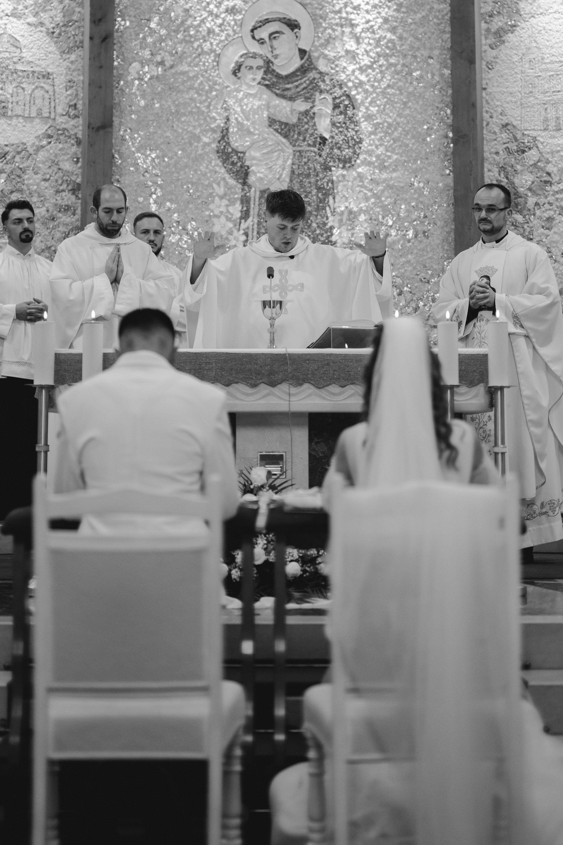 Black and white photo of a Catholic wedding ceremony with priests at the altar.