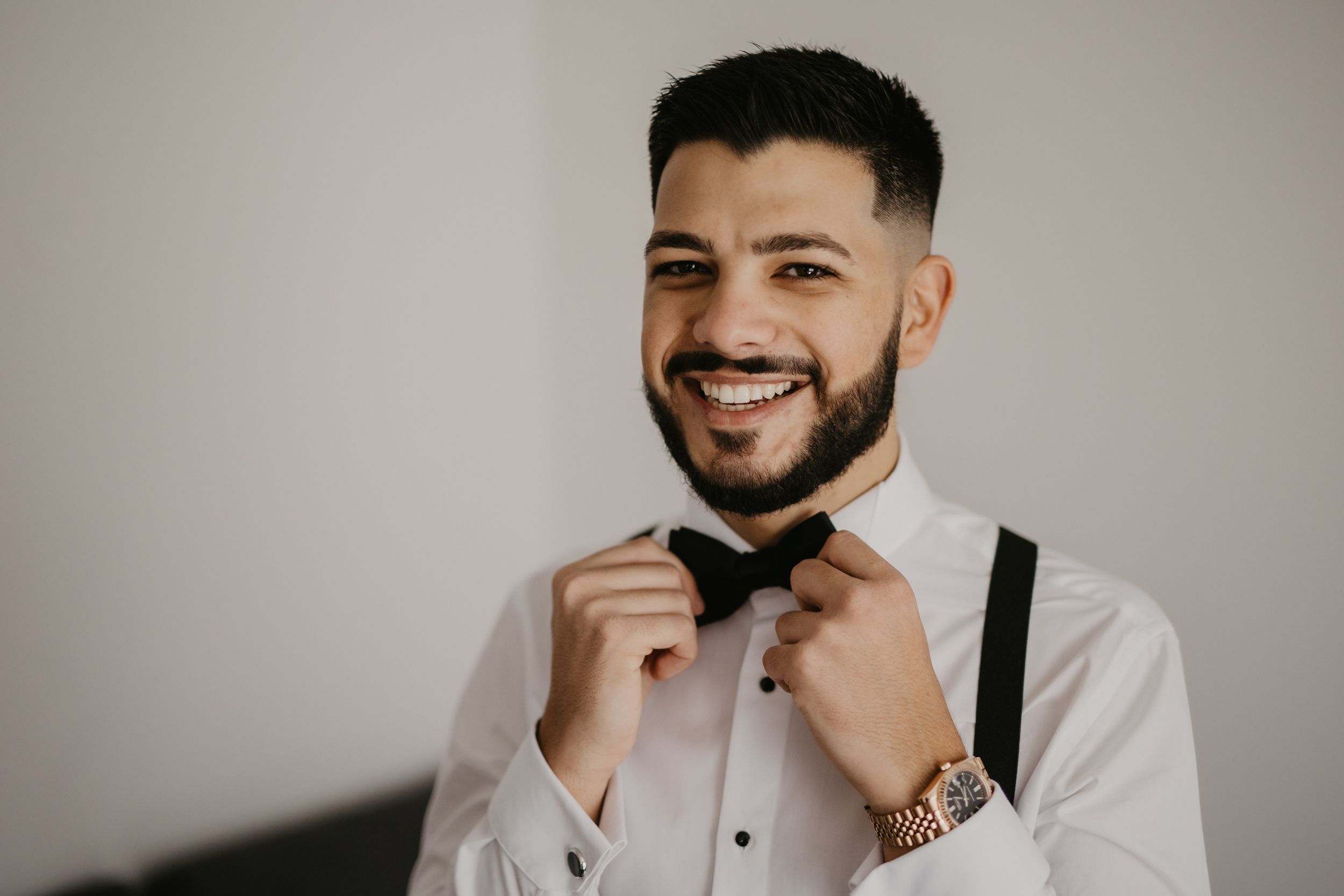 A well-dressed gentleman adjusting his black bow tie while getting ready.