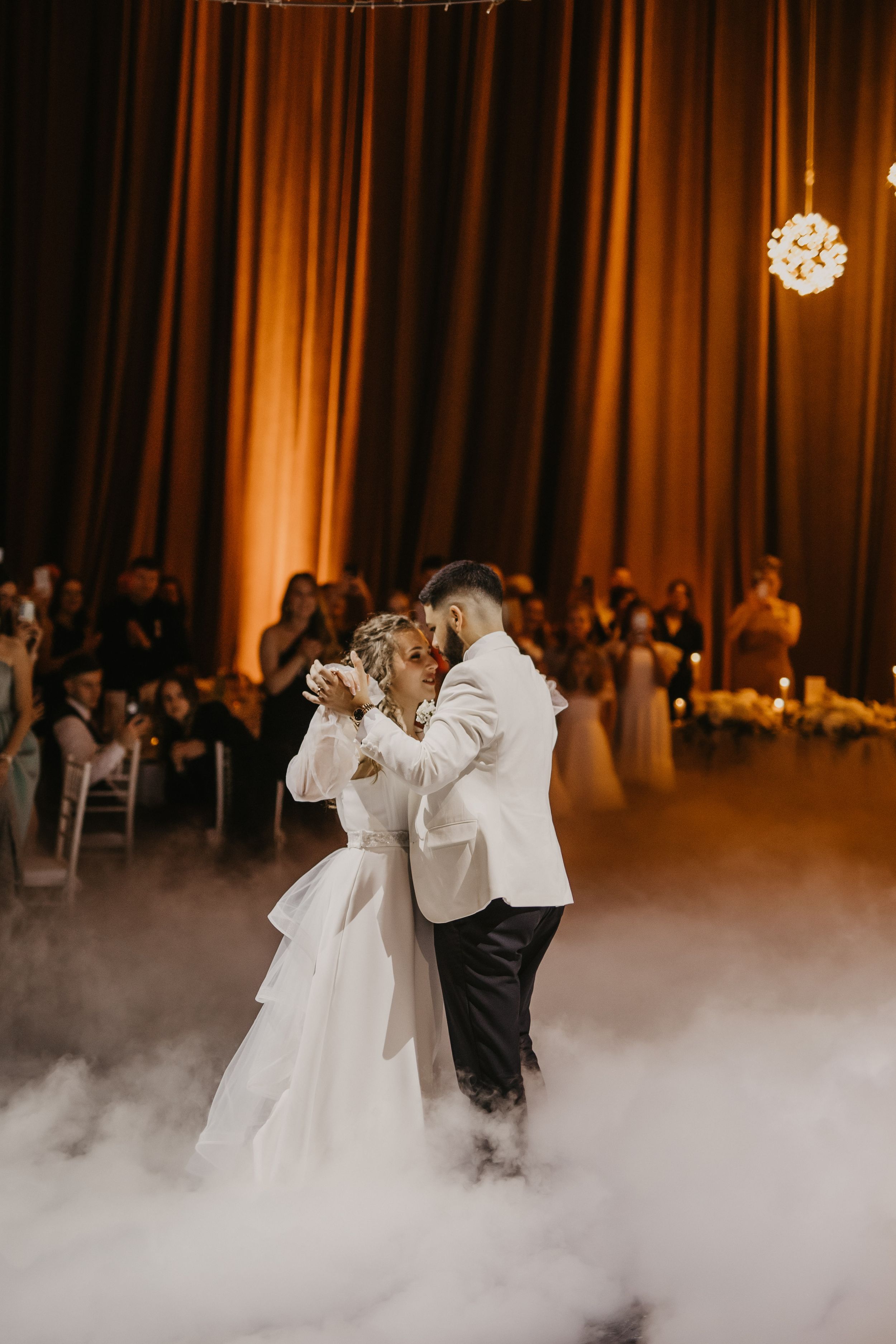 A couple shares their first dance surrounded by fog effects at their wedding reception.