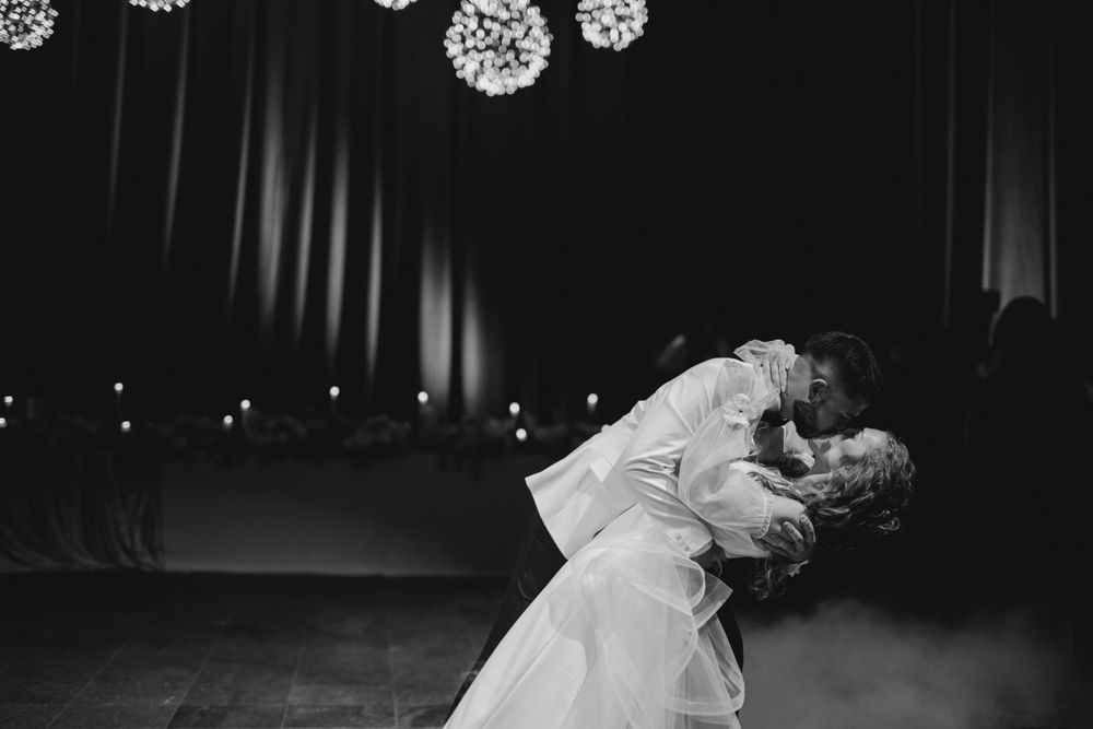 Black and white photo of couple sharing romantic dance dip moment at wedding reception.