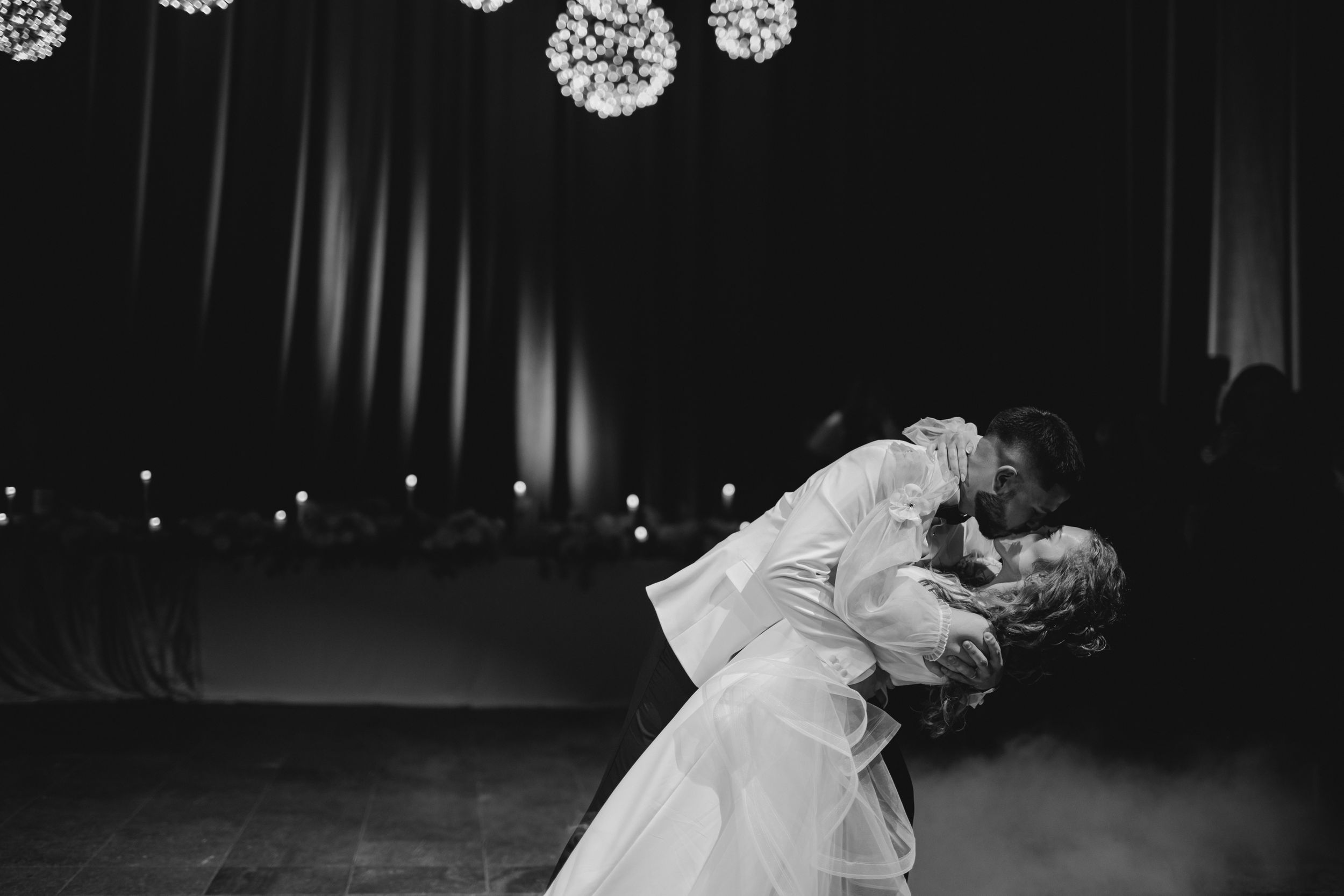 Black and white photo of couple sharing romantic dance dip moment at wedding reception.