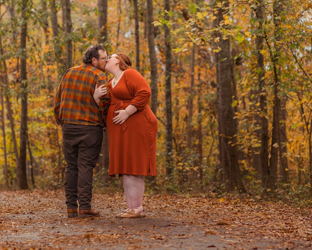 Romantic maternity photo session of a couple walking through an autumn forest in Greenville, SC.