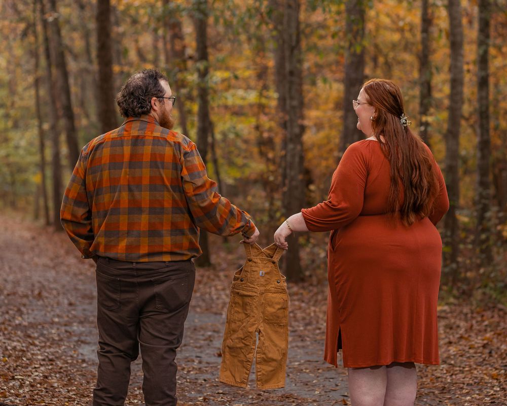 Outdoor maternity photo of a couple walking with soon to be baby during an autumn session in Greenville, SC.