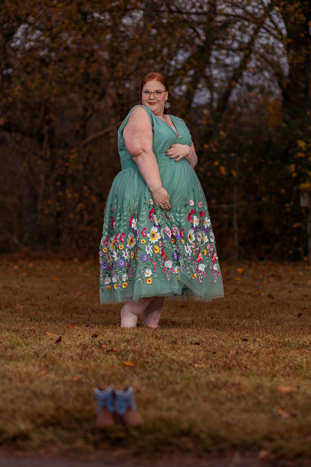 Outdoor maternity portrait in Greenville, SC featuring a woman in a teal floral dress during autumn.