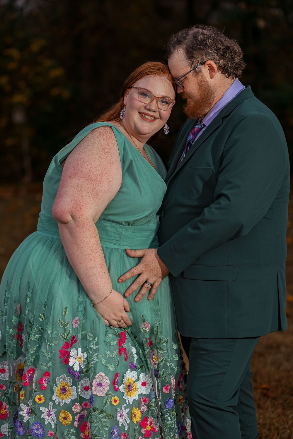 Outdoor maternity photo session in Greenville, SC featuring a couple embracing during an autumn shoot.
