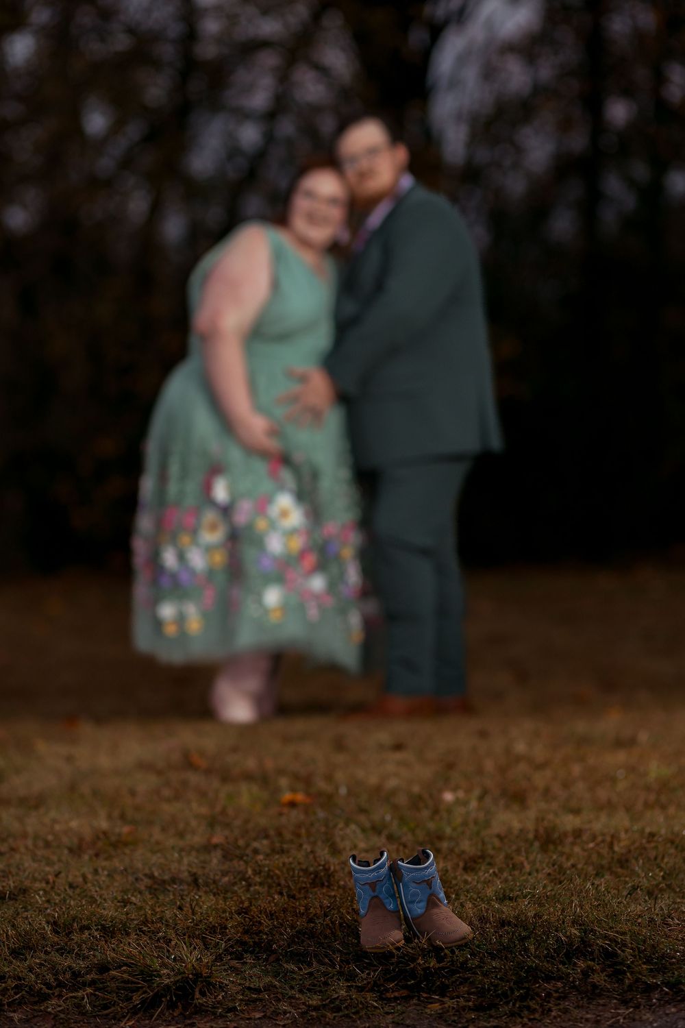 Maternity photo of a couple with baby shoes in the foreground during an outdoor session in Greenville, SC.