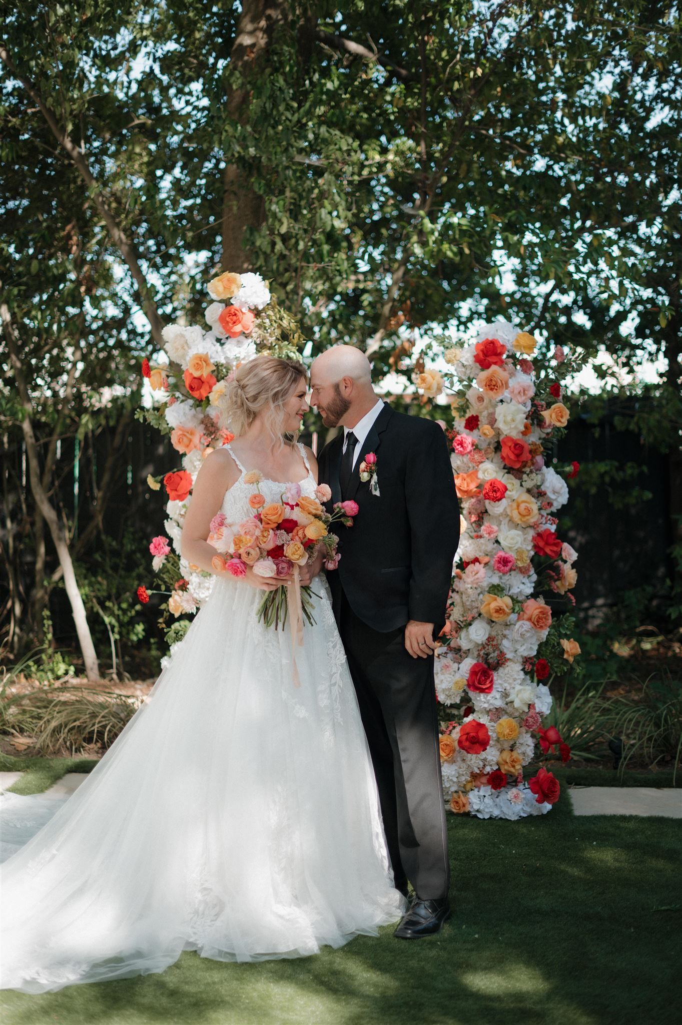 A romantic garden wedding ceremony with a floral arch adorned in pink and white blooms at the Juliana in Houston.