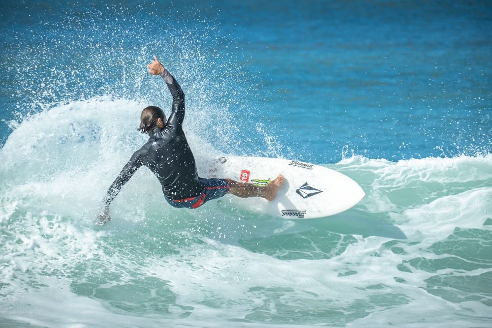 Dynamic surfing action shot showing aerial maneuver on a breaking turquoise wave.