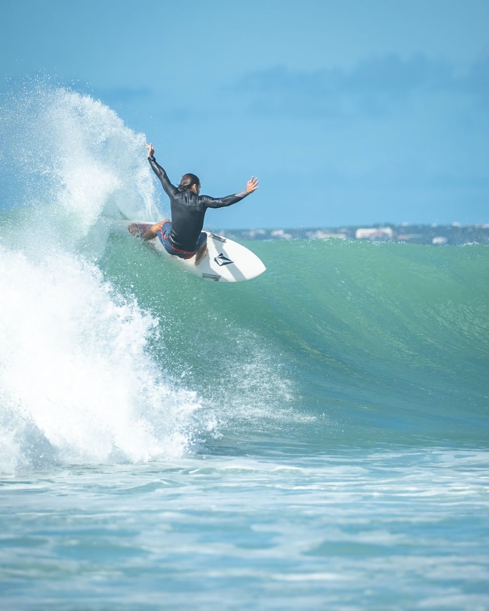 Skilled surfer executing aerial trick on top of cresting turquoise wave.