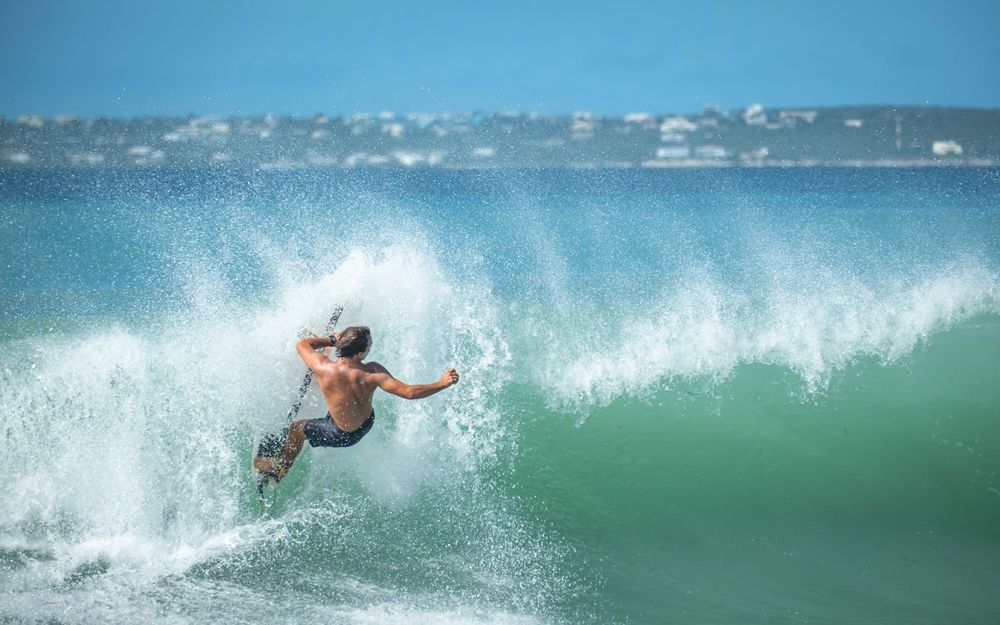 Surfer performing stylish cutback maneuver on emerald green wave face.