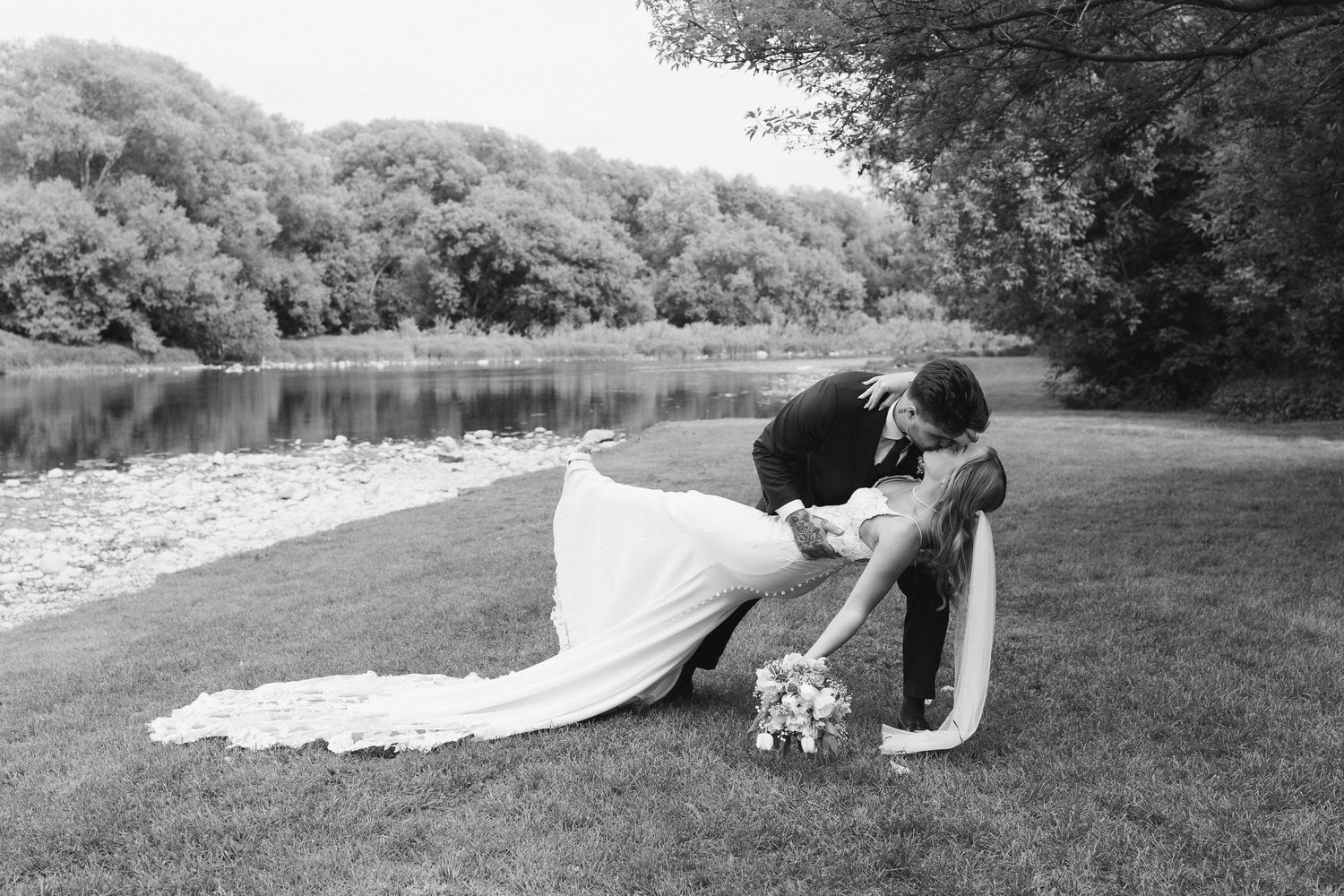 A newlywed couple in a deep dip kiss after their wedding at Timberbarn in St Jacobs, black and white
