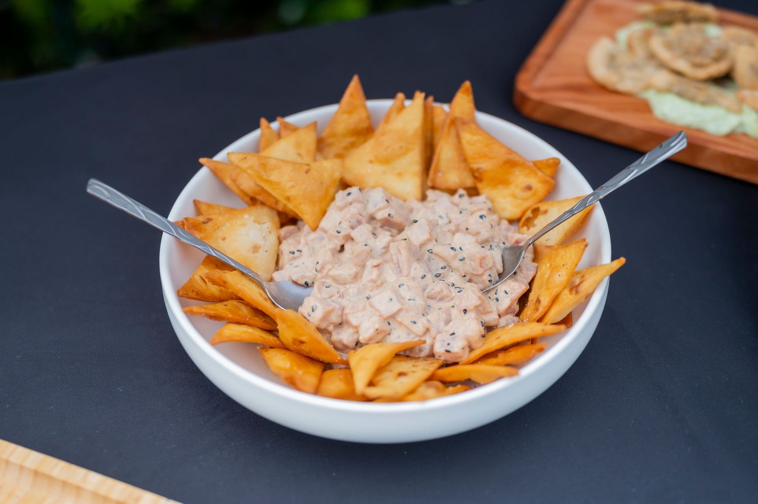 A white bowl filled with tortilla chips surrounding a creamy tuna or chicken salad dip in the center.