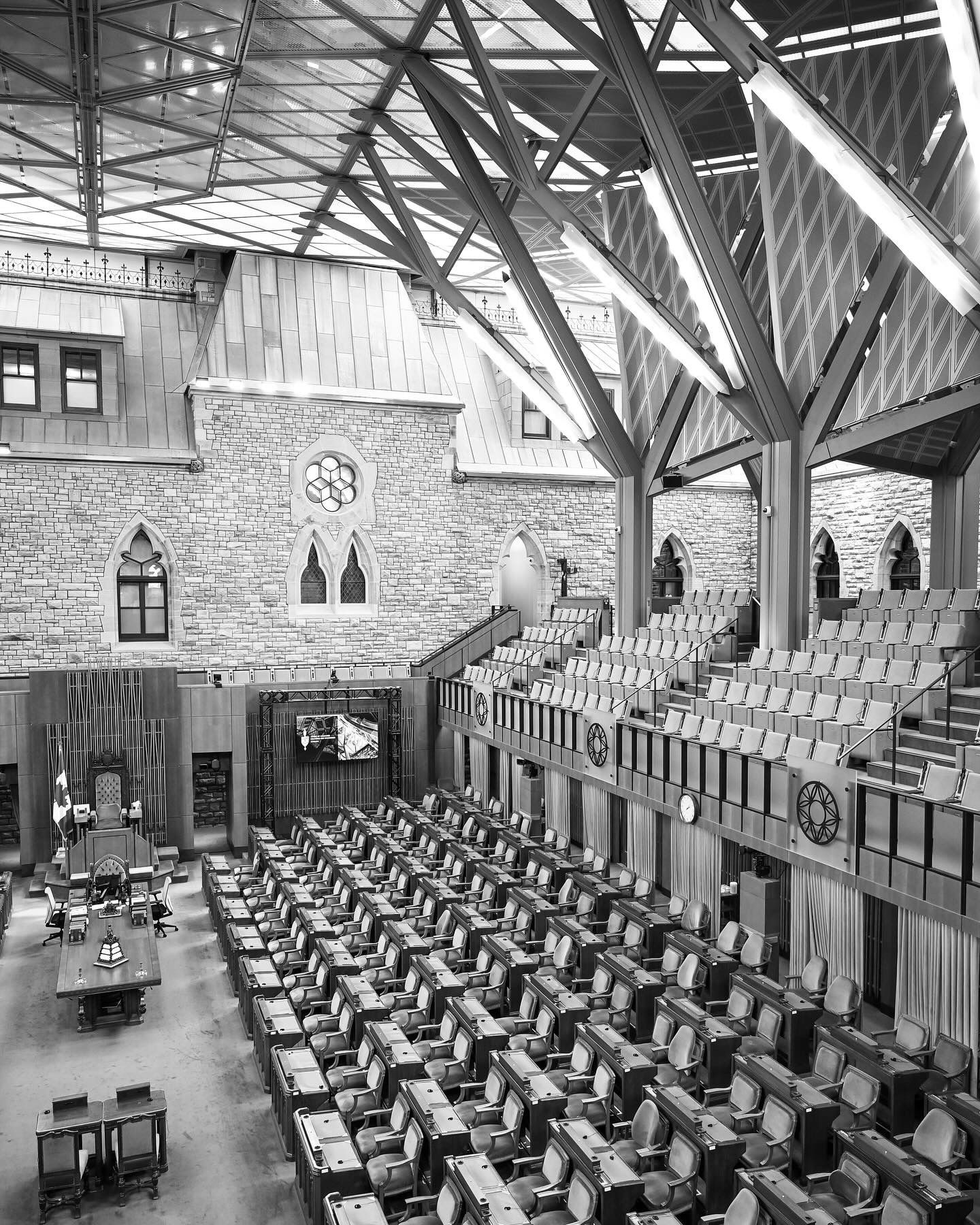 Historic parliament assembly hall with tiered wooden seating and Gothic architectural details.