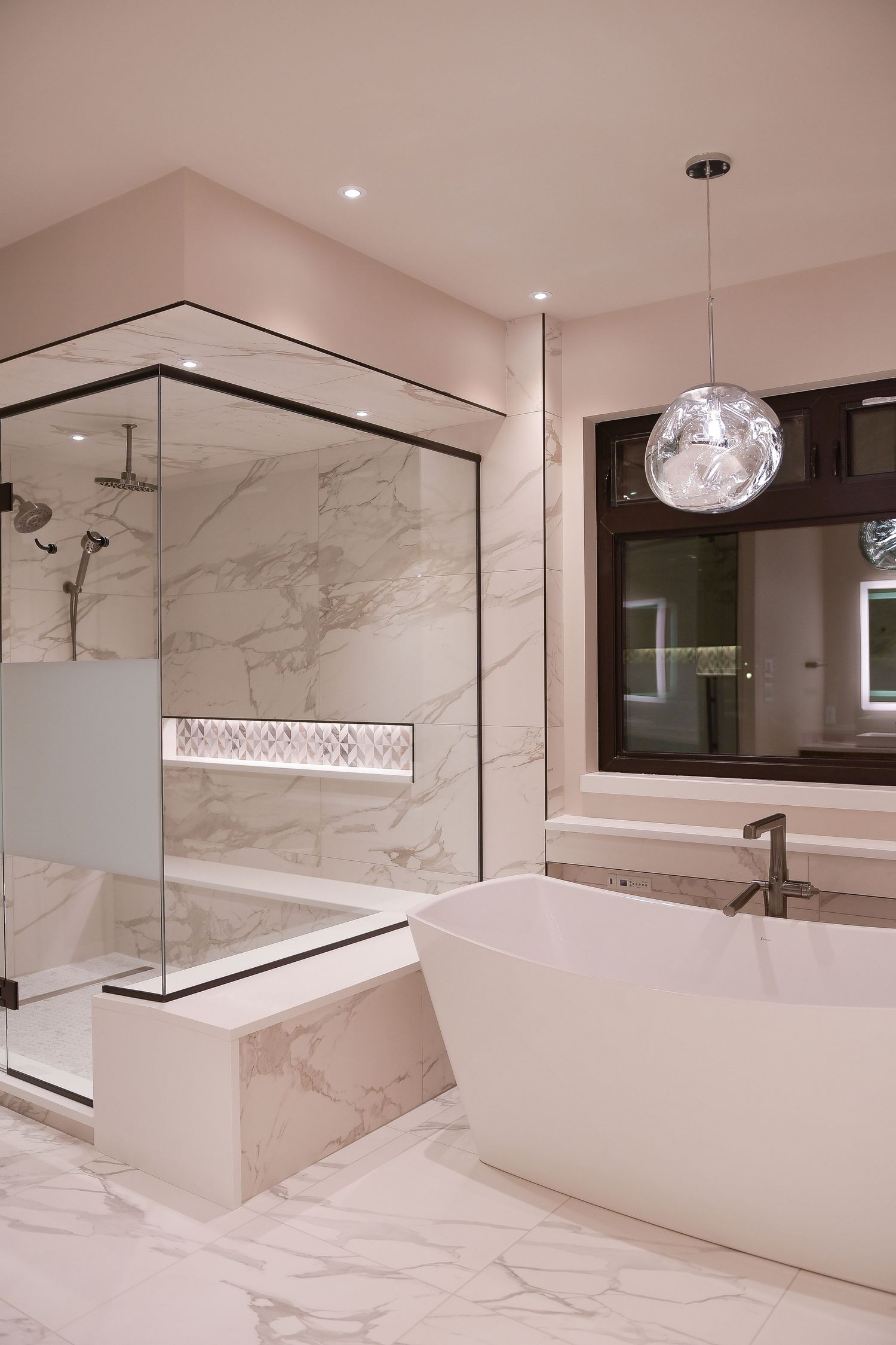 Luxurious marble bathroom with freestanding tub and glass shower enclosure.