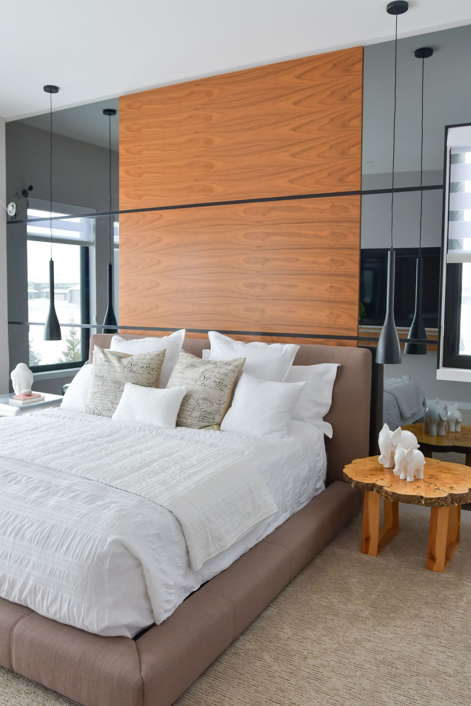 Modern bedroom with wood paneled wall and white bedding featuring pendant lighting.