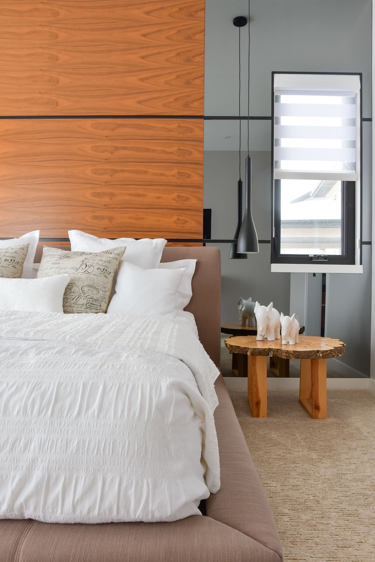Contemporary bedroom featuring wood accent wall and white bedding with black pendant lights.