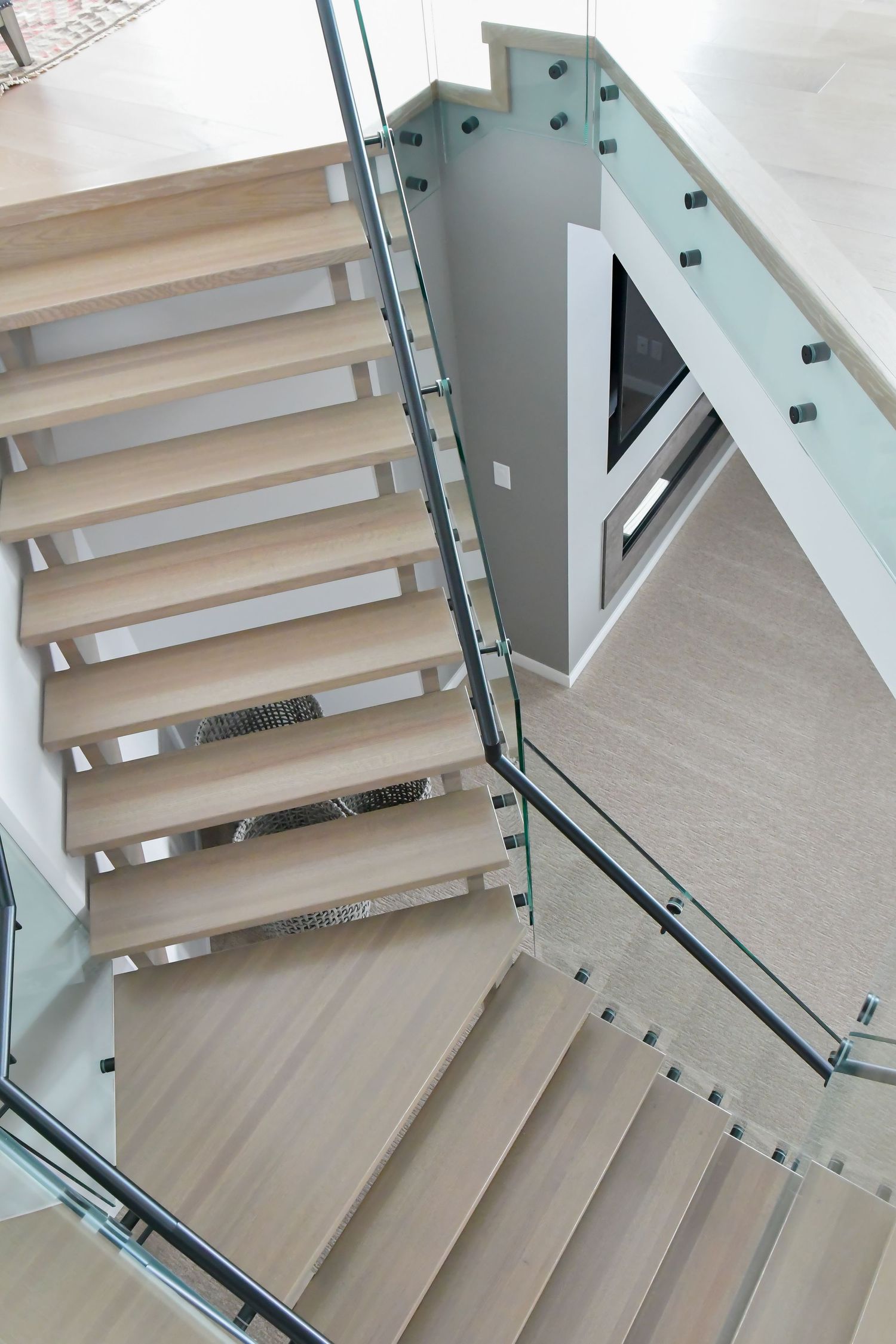 Modern floating staircase with glass railings and light wood treads in contemporary interior.