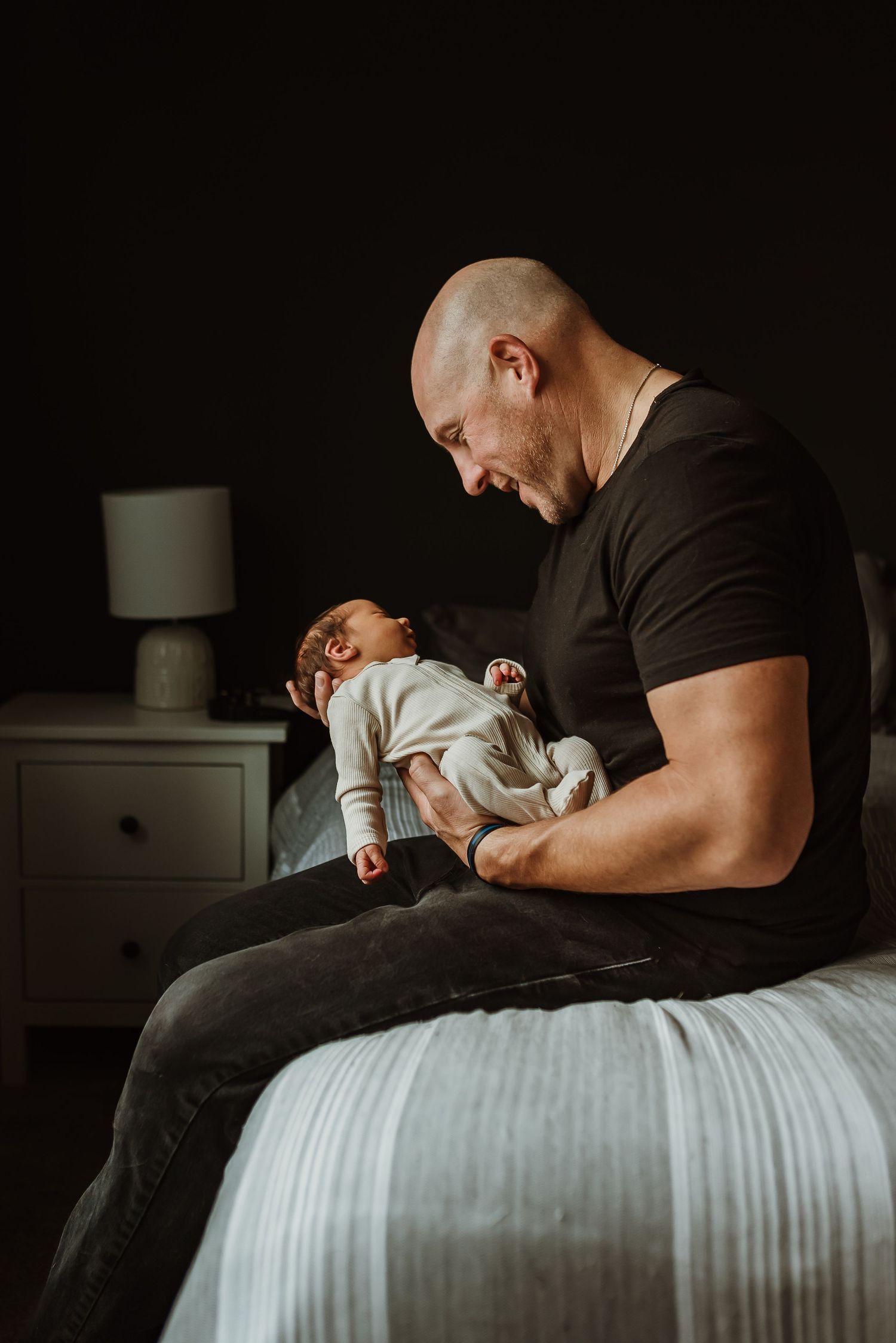 newborn home session dad sitting with baby on bed