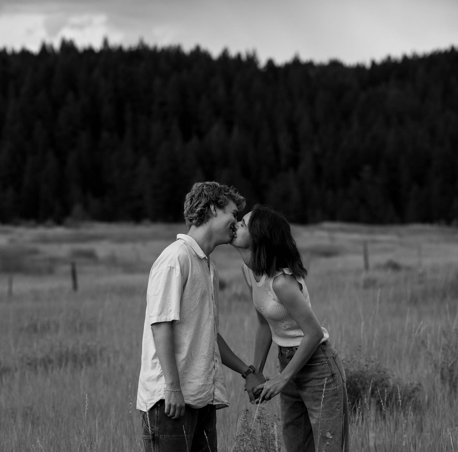 couple kissing and holding hands. both are smiling and happy. in black and white