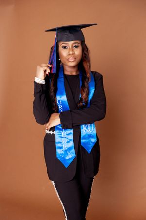 Studio graduation portraits with blue KU stole against warm brown background.