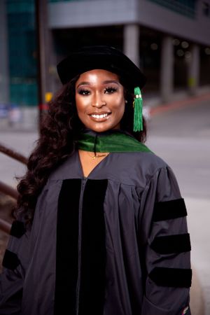 Outdoor graduation photo series in traditional black academic regalia with green accents.