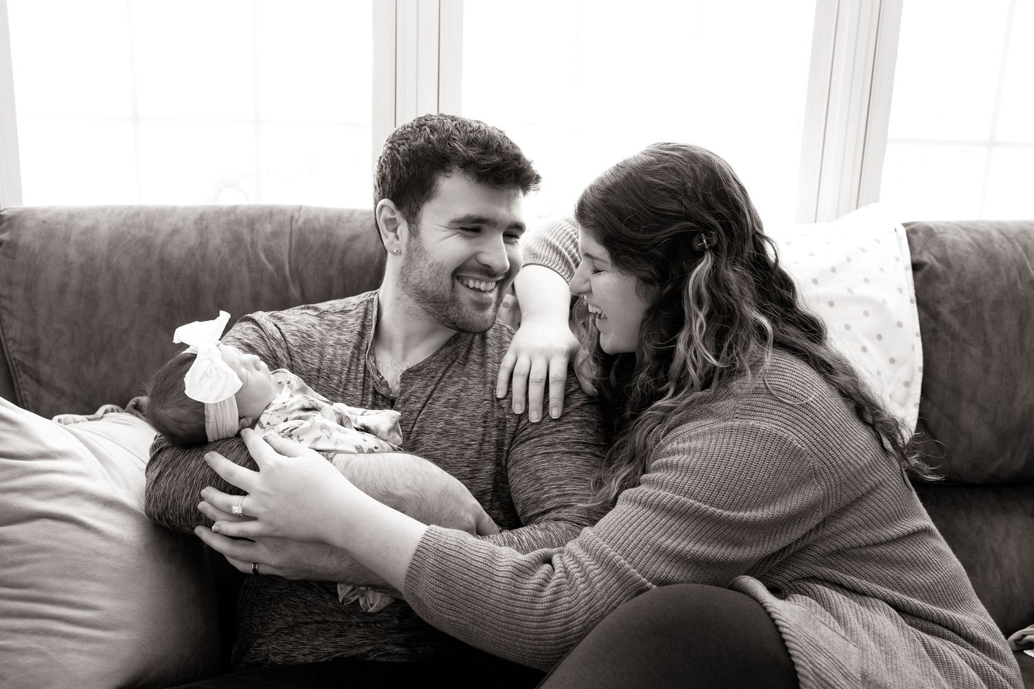 Couple sharing intimate moment on couch in black and white photo series.