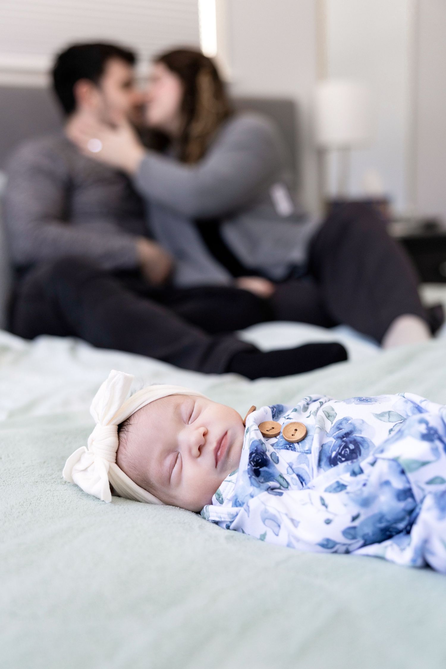 Sleeping infant in blue and white patterned outfit on mint green bedding.